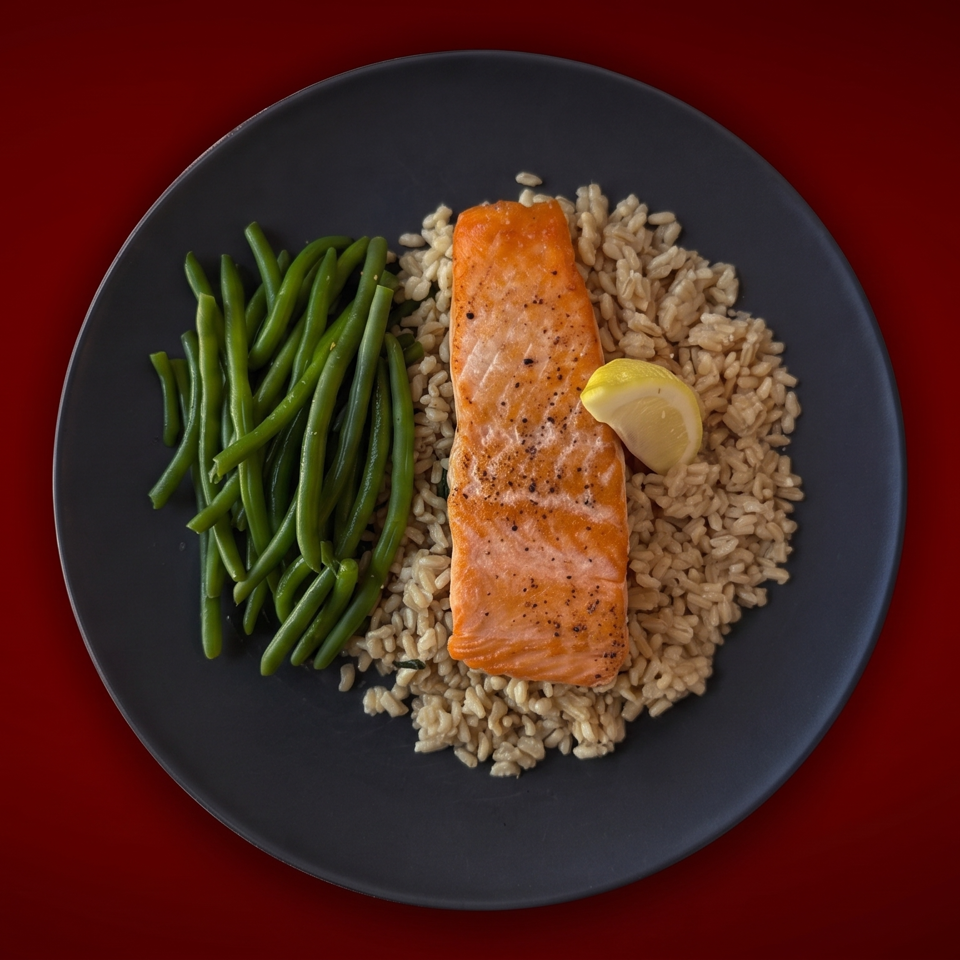 Grilled salmon with lemon, brown rice, and green beans arranged on a dark plate against a deep red background.